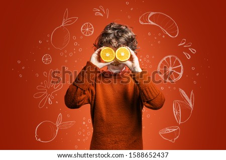 Elementary age kid having fun with oranges. Child with eyes covered with orange slices. Illustration sketches in background. Fruit, Vitamin C and healthy lifestyle concept.