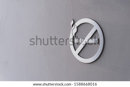 Stainless steel non smoking sign hanging on sandstone wall of business skyscraper
