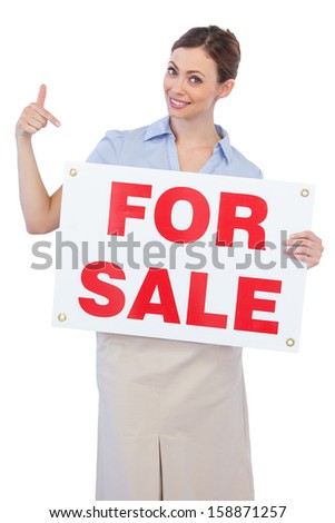 Happy estate agent posing and pointing to for sale sign on white background