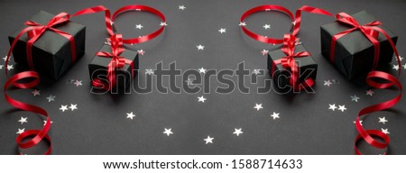Xmas background. Black Christmas gifts, ornaments on black background. Winter holiday present. Merry Christmas and Happy Holidays greeting card, frame, banner