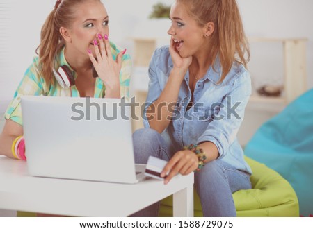 Two friends buying on line with credit card and a laptop
