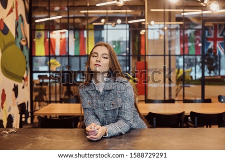 Fashion photo of a girl indoors. Beautiful girl in a hostel, restaurant, university, language school, on the background of flags.