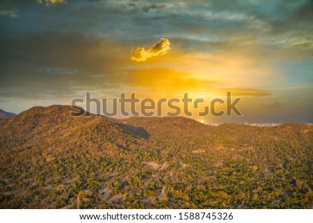 This unique photo shows the nature landscape with trees and hills from above with a unique cloudscape in the sunset in Hua Hin Thailand. The picture was taken with a drone.