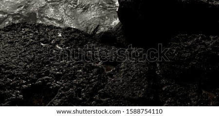 Black lava on the beaches of Hawaii with water running off