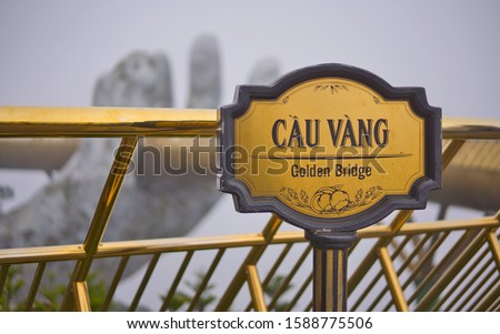 Banner of top famous attraction place and landmark, Golden Bridge (Cầu Vàng / Cau Vang), on Ba Na Hills, Da Nang City, Vietnam, Asia with background of large hand of Mother Nature on foggy winter day