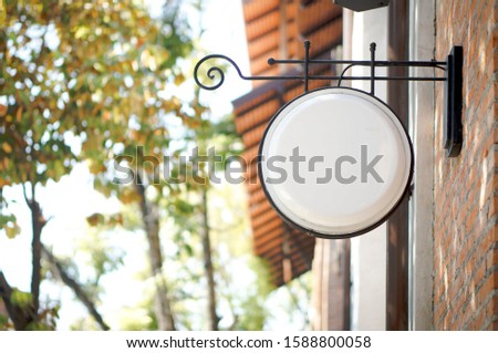 Blank white signboard mockup hanging on brick wall in street environment. Close up view. Vintage, stylish, chic, store sign for shop, restaurant, cafe. Copy Space.