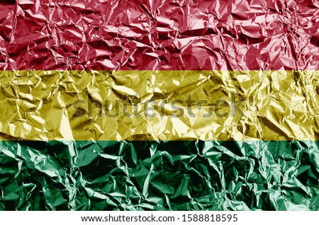 Bolivia flag depicted in paint colors on shiny crumpled aluminium foil closeup. Textured banner on rough background