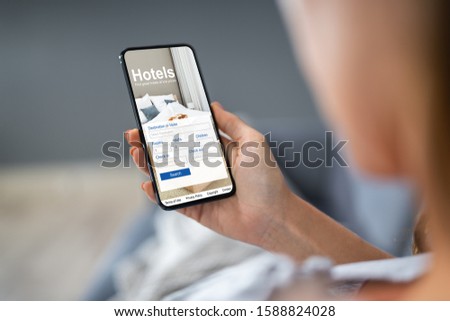Close-up Of A Person Holding A Smart Phone Using Online Low Prices Hotels Application Royalty-Free Stock Photo #1588824028