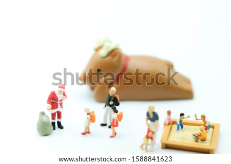Miniature People : Santa in the red cloth with the bag in playground to distribute christmas gift to children use as happy new year concept.