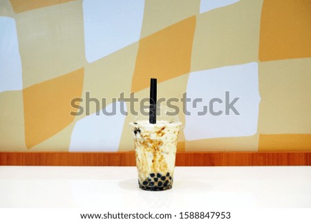 A plastic glass of refreshing iced fresh milk tea with bubble (boba) and brown sugar on table, selective focus.   