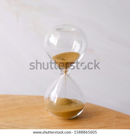 an hourglass on a wooden board with marble background and copy space. 