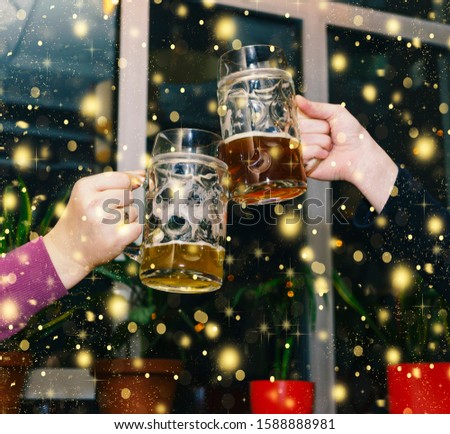 New Years blow with glasses of beer in a pub. Friends celebrate New Year and Christmas.