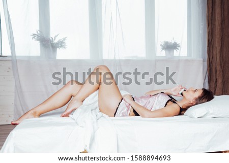 girl in pink underwear lies on the bed talking on the phone