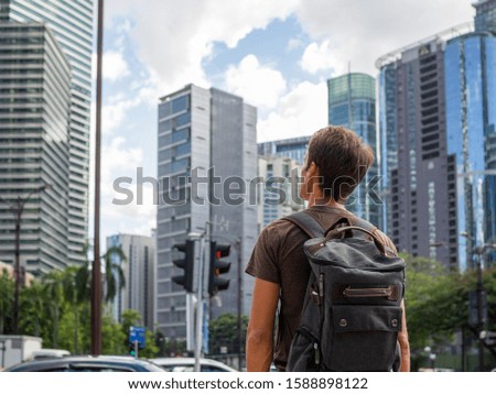 Tourist with backpack looks at skyscrapers in city center