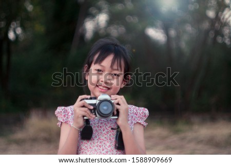 Portrait of asian cheerful little girl taking photo with film camera