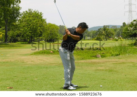 Golfer putting golf in the evening golf course, on sun set evening time. Man playing golf on a golf course in the sun.