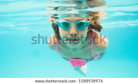 Underwater Young Girl Fun in the Swimming Pool with Goggles. summer concept. Summer Vacation Fun.