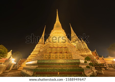Wat Phra Chetuphon or Wat Pho, a Buddhist temple illuminated at night in Bangkok City, Thailand. Thai architecture buildings background in travel trip and holidays vacation concept.