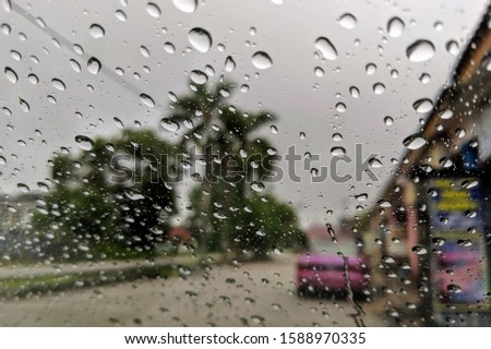 window of the car during rainy day with water eye drops
