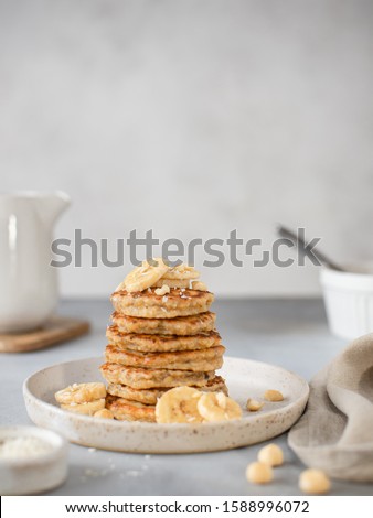 healthy breakfast, oat pancakes with banana and nuts. gray background, vertical image