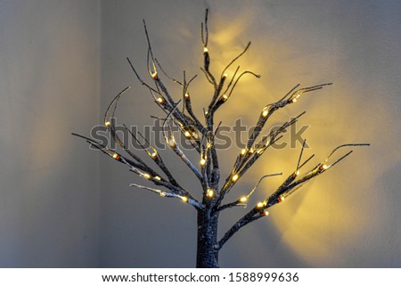 Little Christmas tree with lights reflecting on the wall behind it.