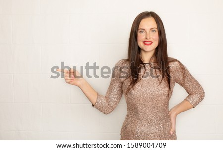 Young elegant woman pointing at white background.