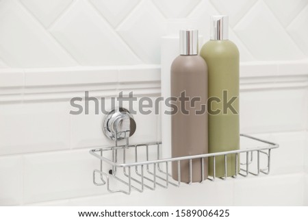 Toiletries bottles on suction cups compact bath shelf, fixing on tiled wall without drilling Royalty-Free Stock Photo #1589006425