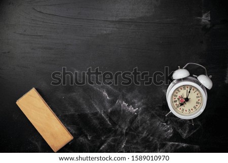 blackboard eraser with white alarm clock on blackboard for background, chalkboard texture for Education background