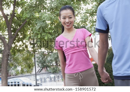 Young woman holding boyfriend's hand in park