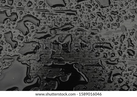 Rain water drops on black surface. Liquid on dark wooden background. Abstract concept with dark mood.