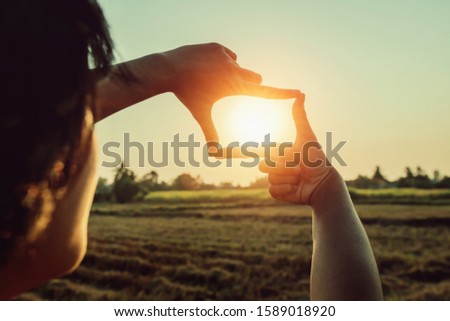 woman hand framing view distant over sunset. business concept