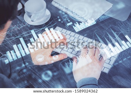 Multi exposure of graph with man typing on computer in office on background. Concept of hard work.
