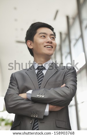 Young businessman with arms crossed smiling