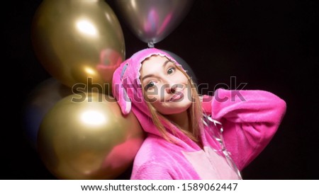 girl in pink kigurumi pajamas with balloons. pajama party.