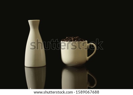 White vases and white coffee cups on a black glass table, with the shadow of the vases and cups, black background