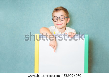 Young boy holding white blank board on blue background