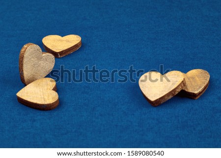 Small wooden hearts on a blue cardboard background for design for Valentine's Day.