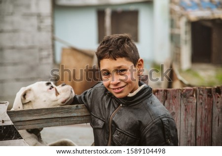 A beautiful little gypsy in a leather jacket on the street with his white dog