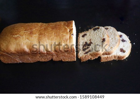 A high angle picture of a white cut pastry with raisins on a black table