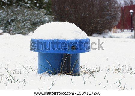 Blue water well pipe on a snowy lawn