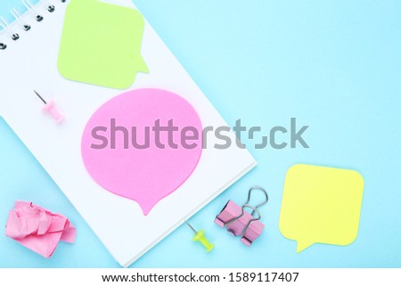 Blank notepad with paper speech bubbles and clip on blue background