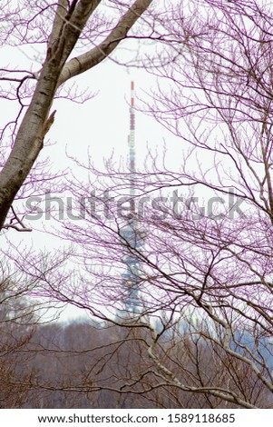 A vertical picture of a tv and radio tower on the Mount Medvednica covered with trees in Zagreb