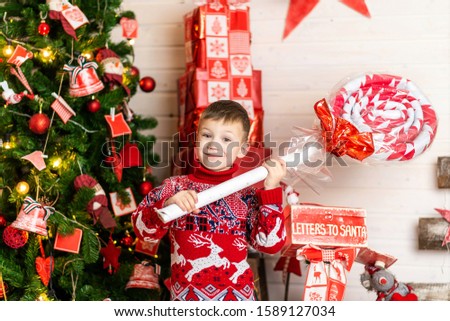 New year and Christmas. A boy in a red Christmas sweater on the background of a Christmas tree