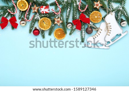 Christmas tree branches with toys and orange fruits on blue background