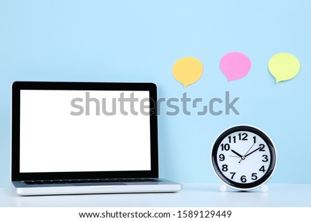 Laptop computer with round clock and blank speech of bubbles on blue background