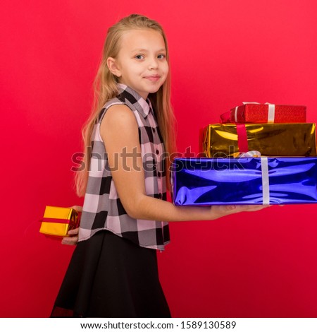 Small child holding birthday present on red background. image