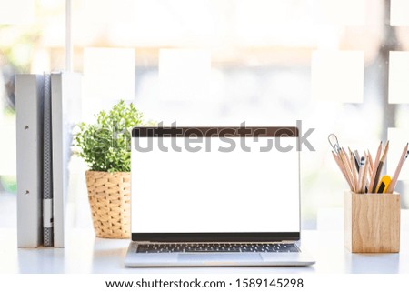 Mock up image of computor laptop with blank white screen background in the working space for advertising and text. 