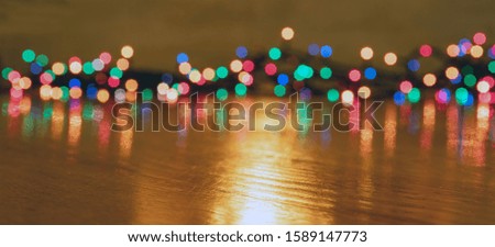 Christmas lights glowing. Xmas holiday decoration background, banner. Colorful lights garland illuminated, reflections on the wood floor, copy space, banner