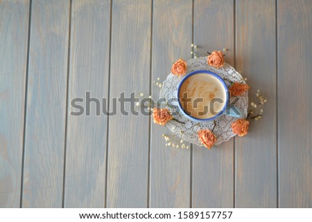 Fresh espresso with vintage little dry roses on wooden table, flat lay image with copy space