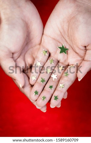Woman or girl showing or holding golden stars on her hand isolated on red vintage background. Concept for Christmas holiday, USA Independence day.